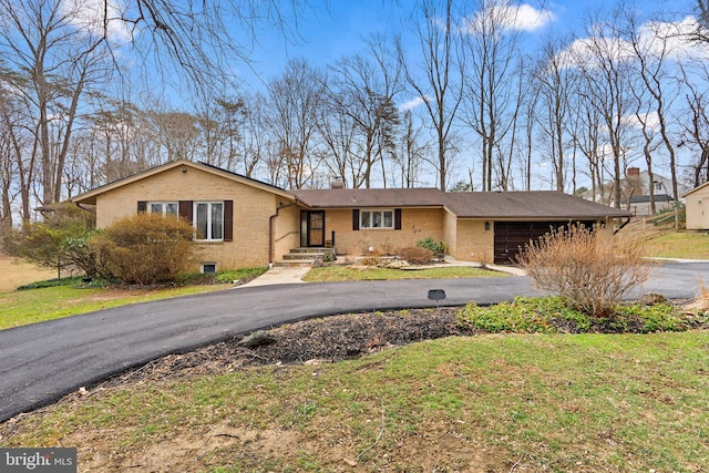 single story home with a chimney, a front lawn, a garage, aphalt driveway, and brick siding