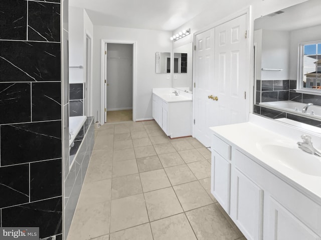 full bathroom with a garden tub, two vanities, a sink, and tile patterned floors