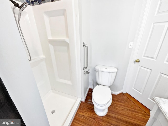 full bathroom with toilet, a shower stall, baseboards, and wood finished floors