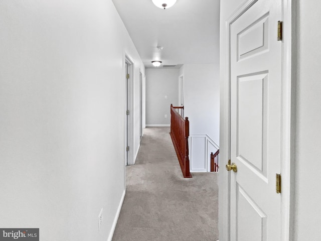 corridor with carpet floors, baseboards, visible vents, and an upstairs landing