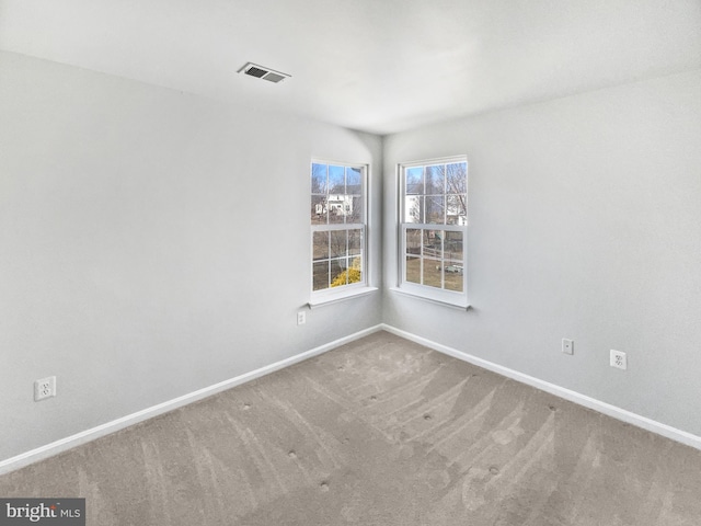 unfurnished room featuring carpet, visible vents, and baseboards