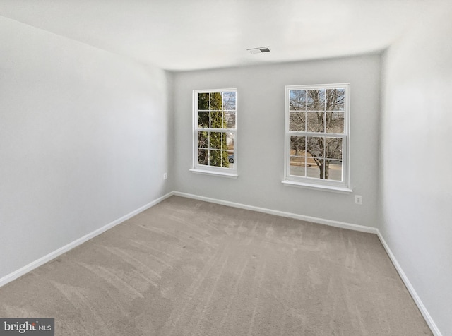 carpeted empty room featuring baseboards and visible vents