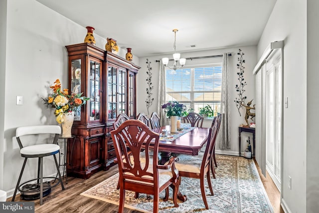 dining area with baseboards, visible vents, an inviting chandelier, and wood finished floors