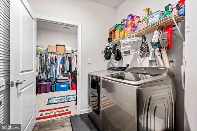 laundry area with laundry area, visible vents, washing machine and clothes dryer, and wood finished floors