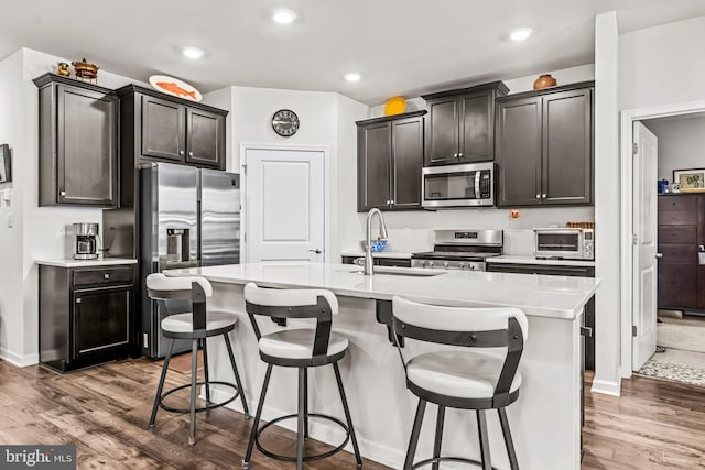 kitchen with appliances with stainless steel finishes, a breakfast bar, a sink, and dark wood finished floors