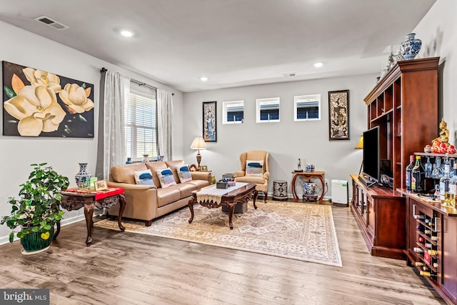 living area featuring light wood-type flooring, baseboards, visible vents, and recessed lighting