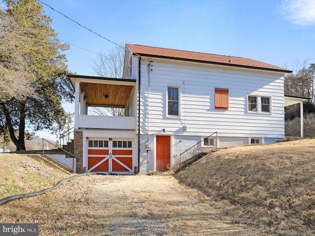 view of side of home with stairway and dirt driveway