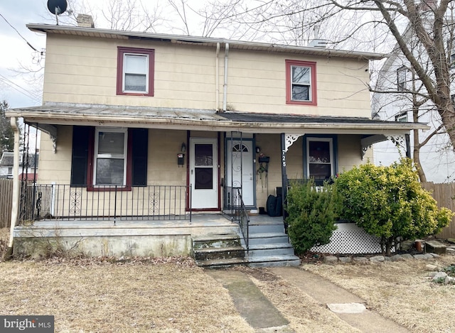 view of front of property with a porch, a chimney, and fence