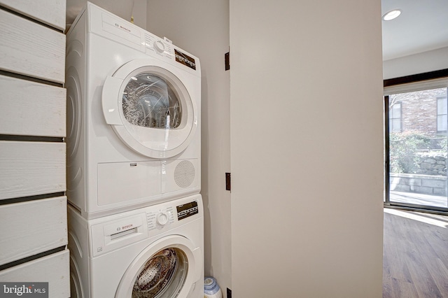 laundry area with laundry area, stacked washing maching and dryer, and wood finished floors