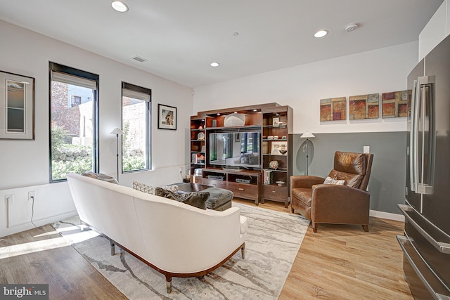 living room featuring baseboards, light wood finished floors, visible vents, and recessed lighting