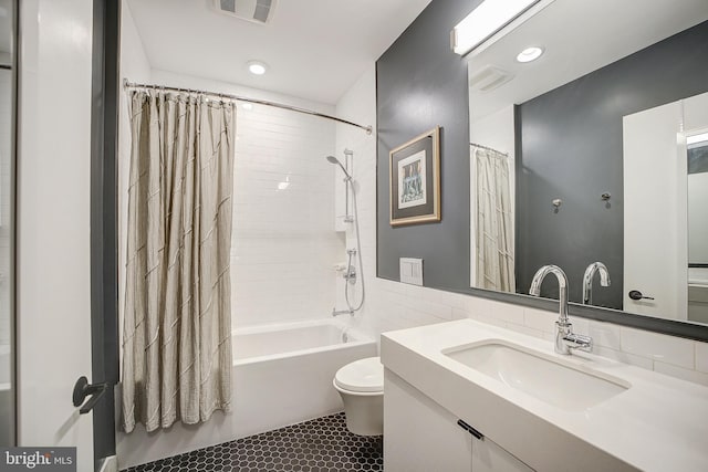 bathroom featuring visible vents, toilet, shower / bathtub combination with curtain, vanity, and tile walls