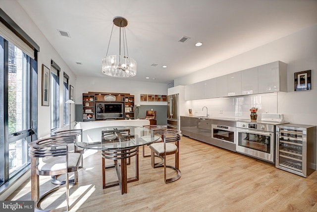 kitchen featuring light wood-style flooring, beverage cooler, a sink, appliances with stainless steel finishes, and modern cabinets