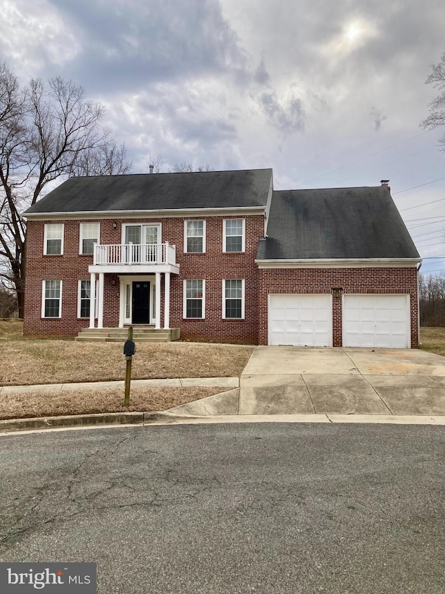 view of front of home featuring brick siding, driveway, and a balcony