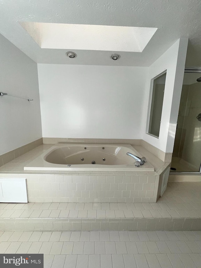 bathroom with a textured ceiling, a tub with jets, tile patterned flooring, and a shower stall