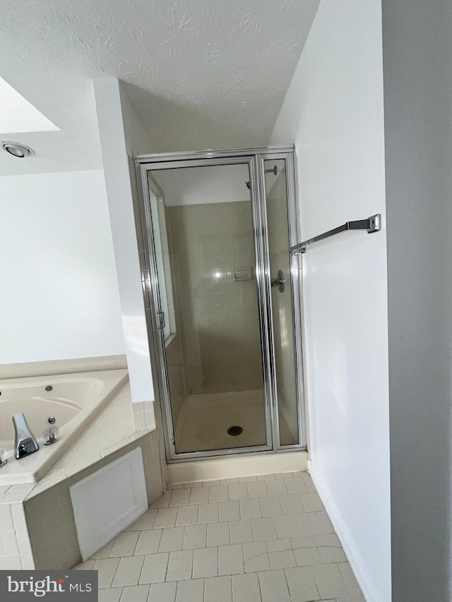 full bathroom featuring a textured ceiling, a shower stall, and a bath