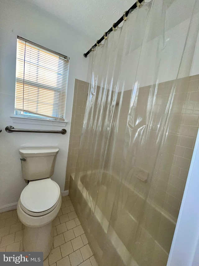 full bath with tile patterned flooring, baseboards, shower / bathtub combination with curtain, and toilet