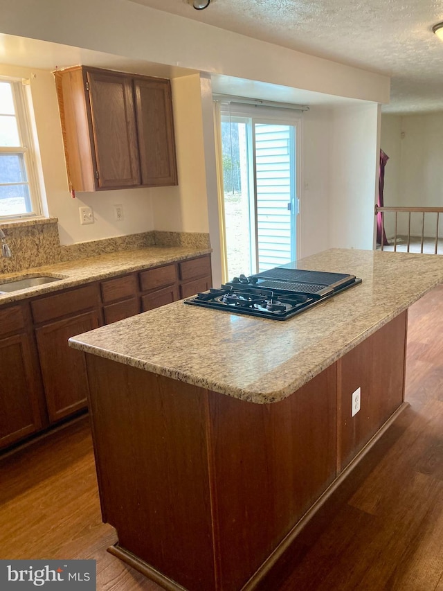 kitchen with black gas cooktop, light countertops, a sink, and wood finished floors