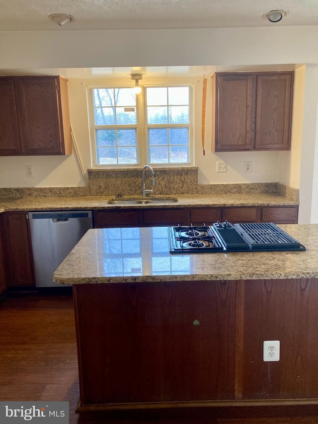 kitchen with light stone counters, a sink, dark wood-style floors, dishwasher, and stovetop with downdraft