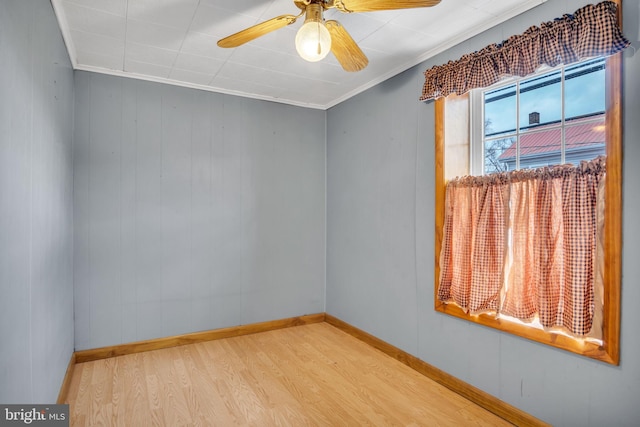 spare room with baseboards, crown molding, a ceiling fan, and wood finished floors