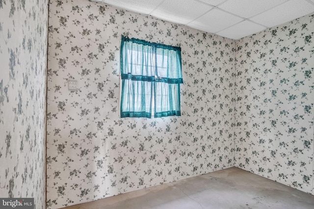 unfurnished room featuring concrete flooring and a drop ceiling