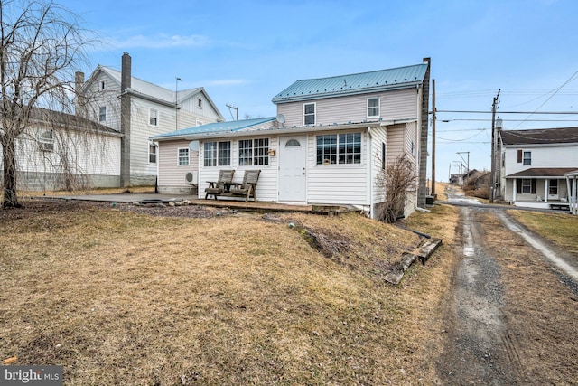 back of property with a yard and metal roof