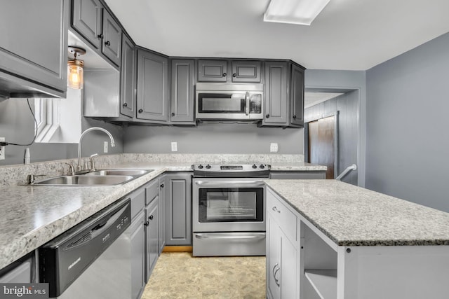 kitchen featuring a kitchen island, appliances with stainless steel finishes, gray cabinets, light countertops, and a sink