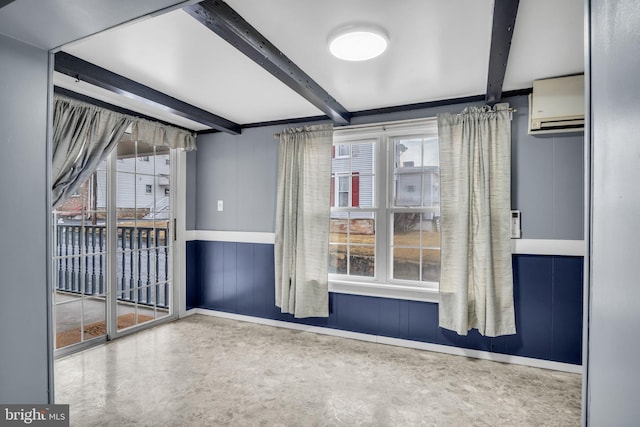 spare room with a wall mounted air conditioner, beamed ceiling, and baseboards