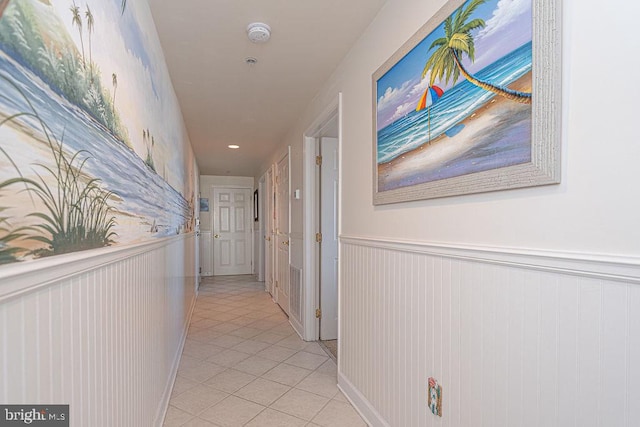 hall with light tile patterned floors and wainscoting