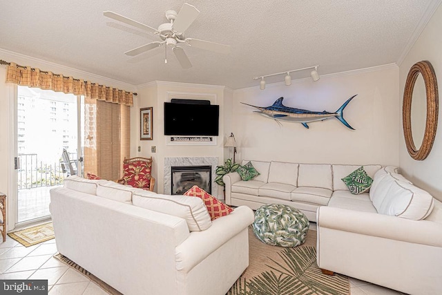 living area featuring light tile patterned floors, a ceiling fan, a textured ceiling, crown molding, and a high end fireplace