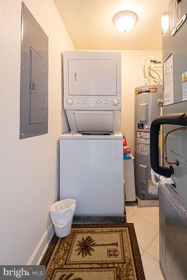 laundry room featuring light tile patterned floors, laundry area, electric panel, stacked washer / dryer, and water heater