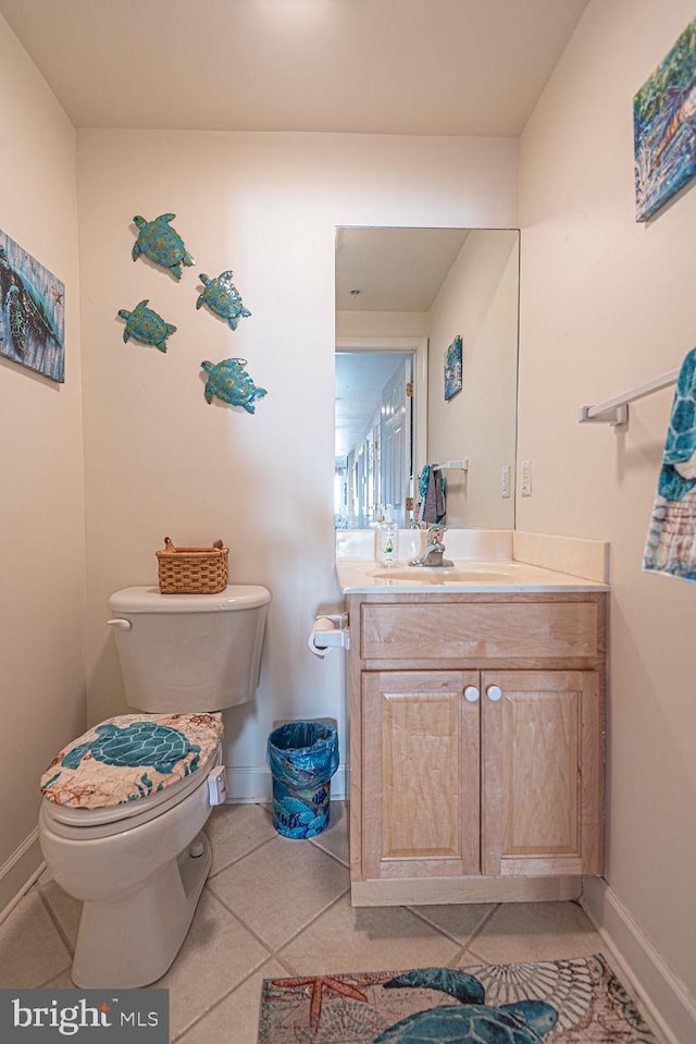 bathroom with toilet, tile patterned floors, baseboards, and vanity