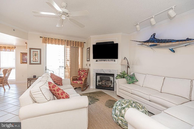 tiled living room with crown molding, a premium fireplace, ceiling fan, a textured ceiling, and baseboards