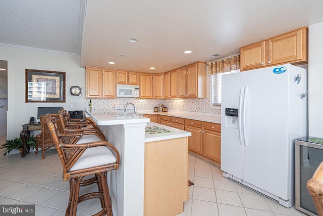 kitchen with white appliances, tasteful backsplash, light tile patterned floors, a breakfast bar, and a sink