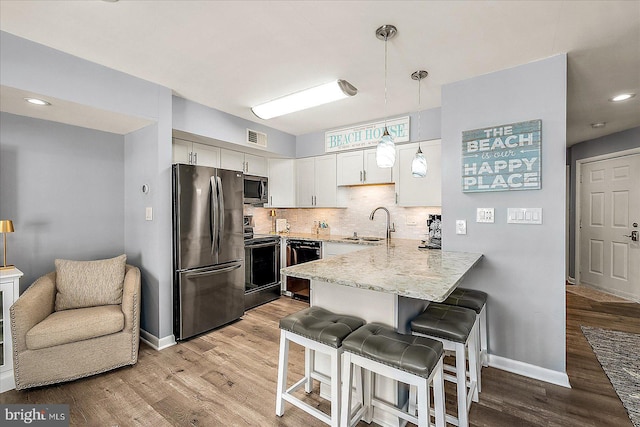 kitchen featuring tasteful backsplash, visible vents, a breakfast bar, a peninsula, and stainless steel appliances