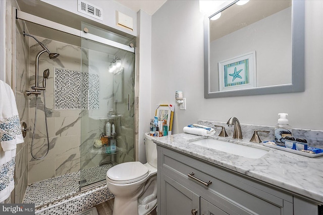 bathroom featuring a marble finish shower, visible vents, vanity, and toilet