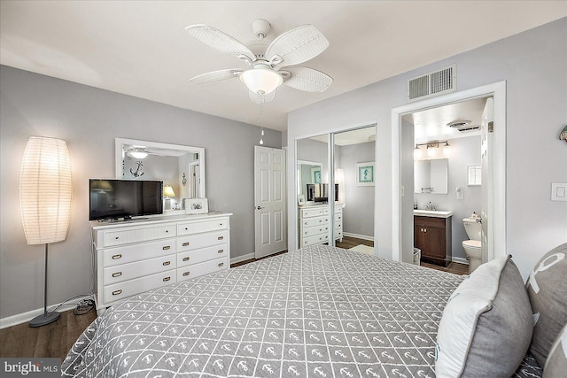 bedroom featuring baseboards, visible vents, wood finished floors, ensuite bathroom, and a closet