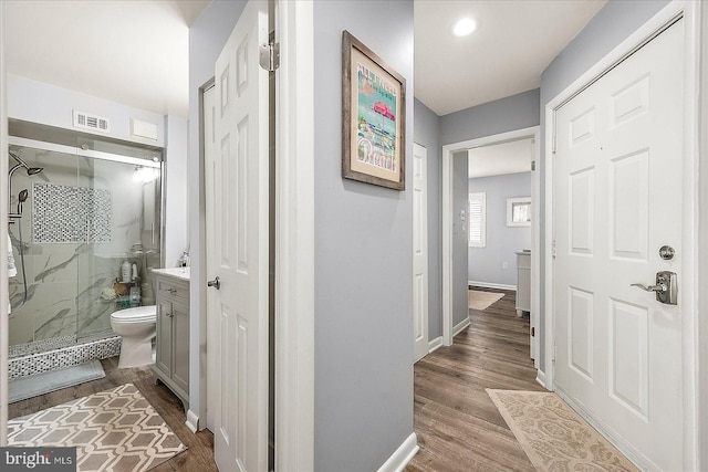 corridor with dark wood-type flooring, visible vents, and baseboards