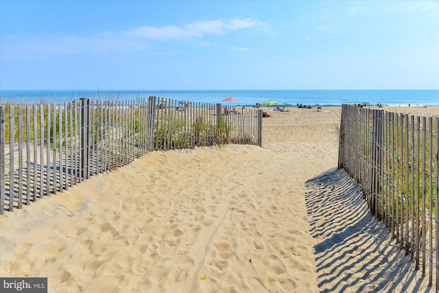 view of water feature featuring a view of the beach and fence