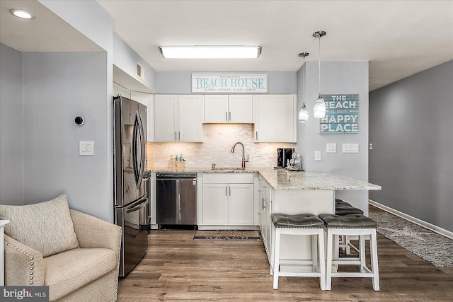 kitchen with white cabinets, dishwasher, freestanding refrigerator, a peninsula, and a sink