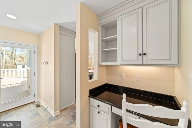 kitchen with dark countertops, visible vents, baseboards, built in study area, and open shelves