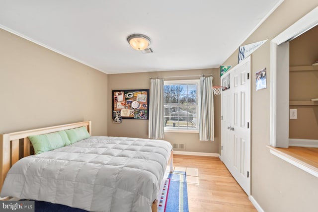 bedroom with visible vents, baseboards, and wood finished floors