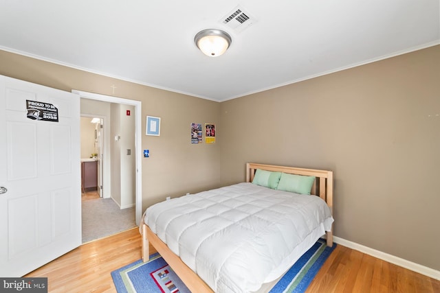 bedroom featuring ornamental molding, light wood-style floors, visible vents, and baseboards