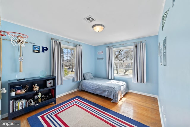 bedroom featuring visible vents, baseboards, and wood finished floors