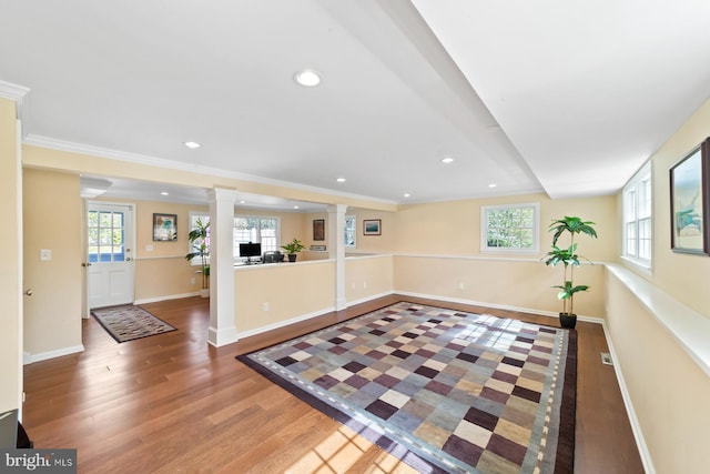 interior space with a wealth of natural light, wood finished floors, baseboards, and decorative columns