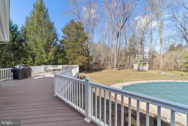 deck featuring a covered pool, a lawn, and a grill