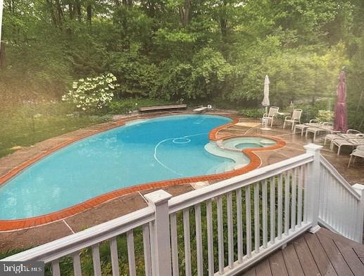 view of pool featuring a pool with connected hot tub and a diving board