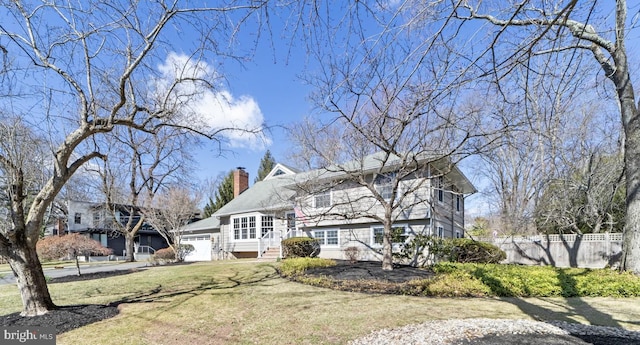 view of front of house featuring a front lawn, fence, a chimney, a garage, and driveway