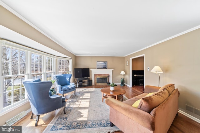 living area featuring visible vents, baseboards, a brick fireplace, and wood finished floors