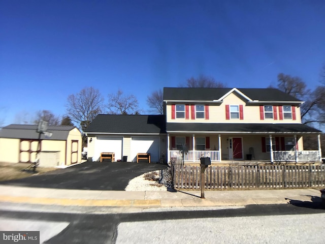 view of front facade featuring aphalt driveway, an attached garage, covered porch, and a storage unit