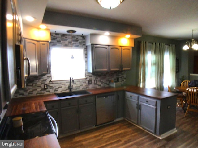 kitchen with a sink, stainless steel appliances, a peninsula, and dark wood-style flooring